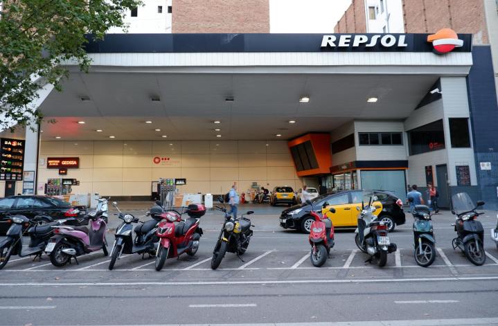 row of motor scooters parked in front of a filling station
