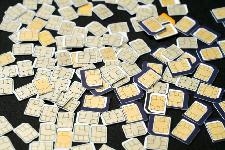 pile of sim cards with gold contacts on black surface